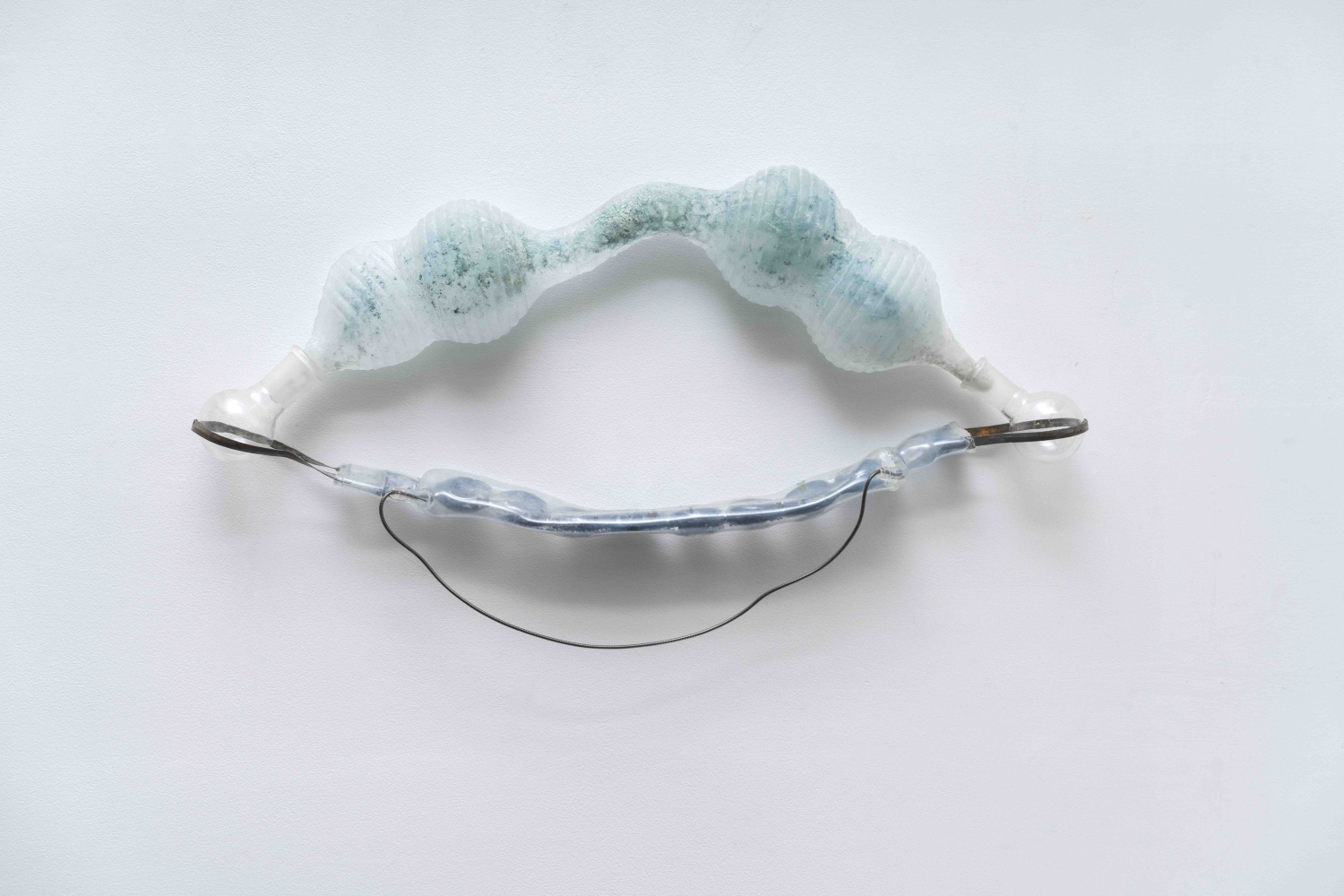 abstract glass wall sculpture in pale blue and clear glass that looks like bellows